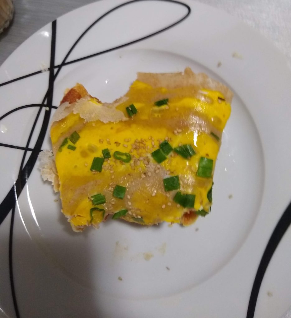 an eggy, green-onion-y crepe-y folded dish with one bite out of it